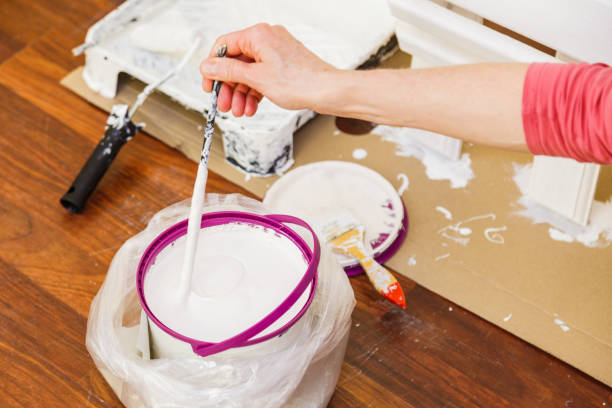 istock Person mixing white paint in bucket. 1489192578