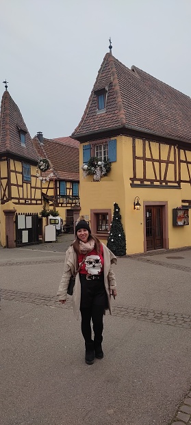 Image of a woman in the beautiful village of Eguisheim during Christmas. There are three different yellow houses, is clearly visible in the picture, so no property release is needed.
