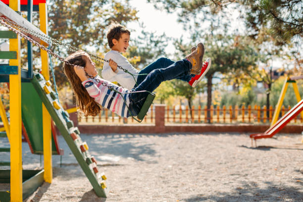Happy children swinging in the park Happy children having fun swinging and enjoying swinging stock pictures, royalty-free photos & images