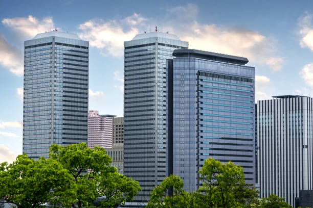 o horizonte urbano moderno de osaka, japão, no verão com árvores em primeiro plano. - office building - fotografias e filmes do acervo