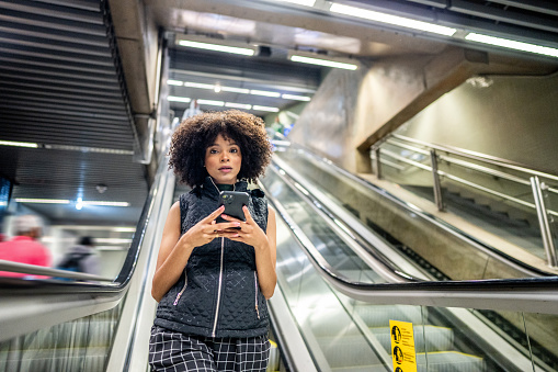 Portrait of a young woman using the mobile phone at the subway station