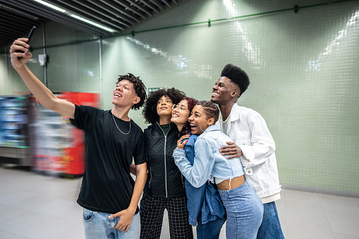 Friends taking selfies on the mobile phone at the subway station