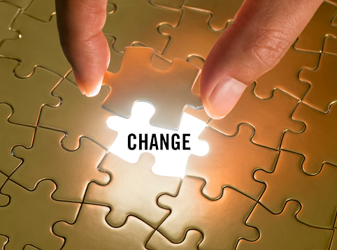Hand holding a puzzle piece with “Change” text underneath
