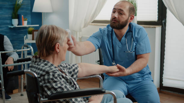 istock Medical assistant using thermometer on old disabled woman 1489206736