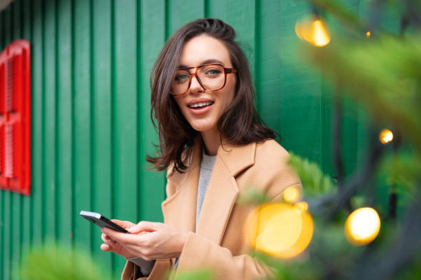 istock Close up smiling woman using smartphone, standing near Christmas tree 1489207148