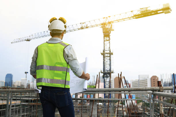 istock construction worker head which is wearing the safety helmet and checking work at the construction site. construction worker engineer architect at work on major construction site with  bule print hardhat and safety vest 1489208342