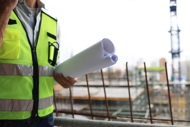 istock construction worker head which is wearing the safety helmet and checking work at the construction site. construction worker engineer architect at work on major construction site with  bule print hardhat and safety vest 1489208356