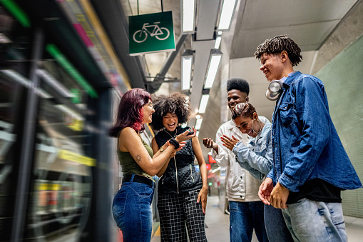 Friends using the mobile phone at the subway station