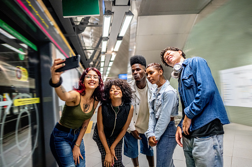 Friends taking selfies on the mobile phone at the subway station