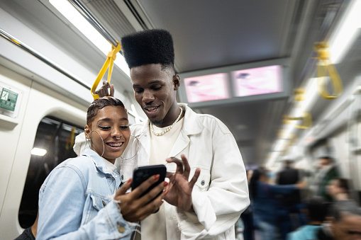 Friends using the mobile phone on the subway train