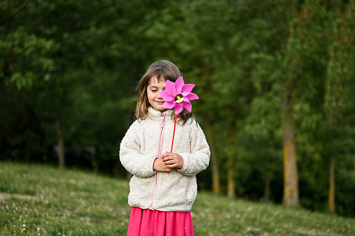 little girl holding pinwheel toy in a meadow.