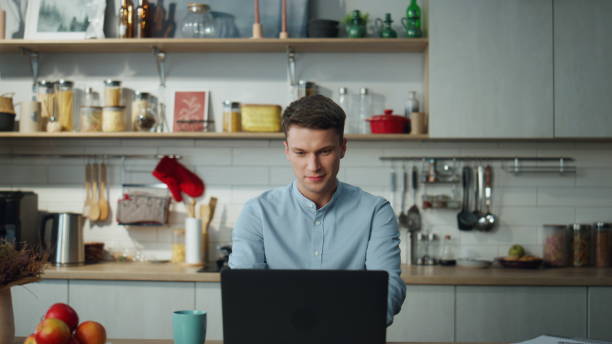 istock Man searching information online sitting at home kitchen. Guy chatting internet. 1489219914