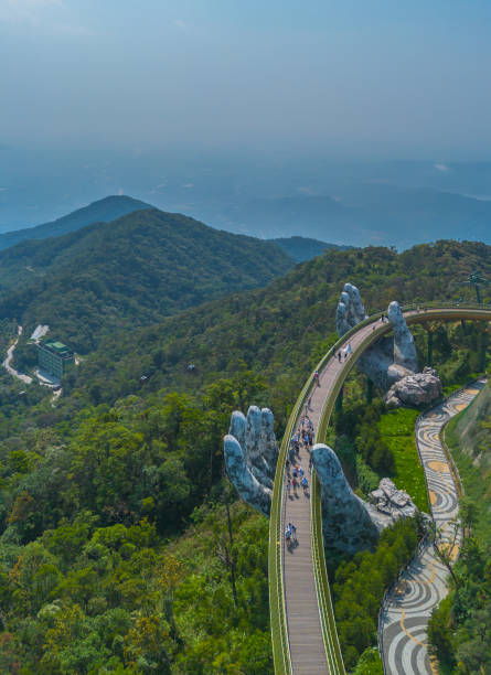 Aerial view of the Golden Bridge in Ba Na hills, Da Nang, Vietnam Aerial view of the Golden Bridge in Ba Na hills, Da Nang, Vietnam. Lifted by two giant concrete hands. Iconic bridge in SunWorld resort and park bridge hand stock pictures, royalty-free photos & images