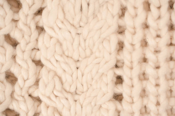 istock A fragment of beige knitted fabric, knitted from white sheep wool. 1489225523