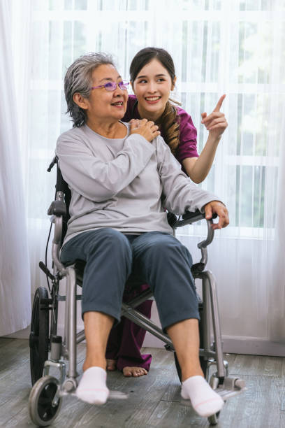 介護看護師は、公園を歩く年配の患者の世話をします。年配の女性を助ける看護師 - happiness women senior adult two people ストックフォトと画像