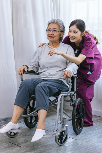Caregiver nurse take care a Senior patient walking in park. Nurse helping senior Woman