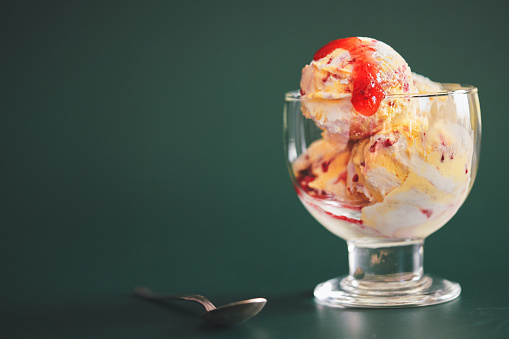 colored balls of ice cream in a glass vase pistachios vanilla icing chocolate cold on a wooden tray table