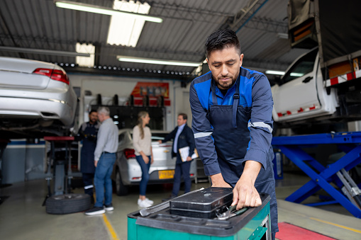 Latin American mechanic using his toolbox while working at an auto repair shop
