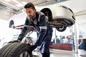 Happy mechanic changing a flat tire on a car