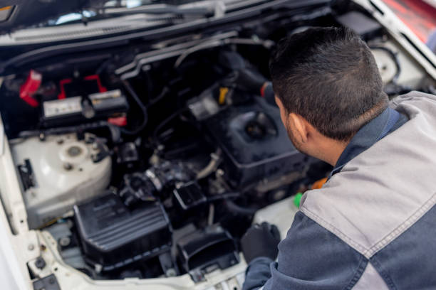 Mechanic checking the oil of a car at an Auto Repair Shop Mechanic checking the oil levels of a car under the hood at an Auto Repair Shop mechanic working under car stock pictures, royalty-free photos & images