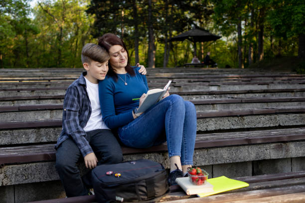 istock Mother and son reading book in the public park 1489231500