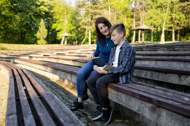 istock Mother and her son reading book in the public park 1489231696