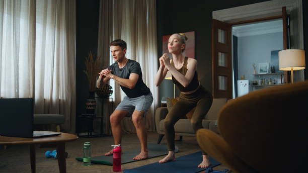 istock Couple squatting training together at home. Family workouting standing on mat. 1489231801