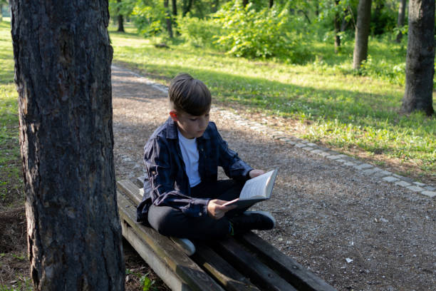 istock Schoolboy reading book in the public park 1489231838