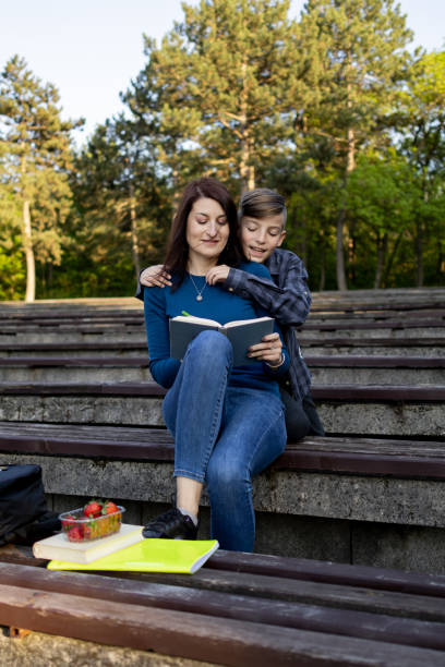 istock Mother and her son reading book in the public park 1489232649