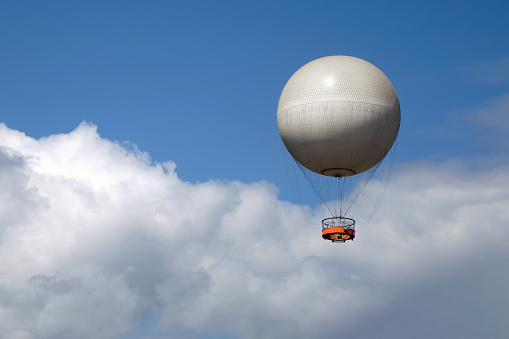 A walking balloon with tourists flies against the background of a blue sky with clouds.