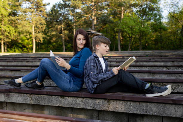 istock Mother and her son reading book in the public park 1489233331