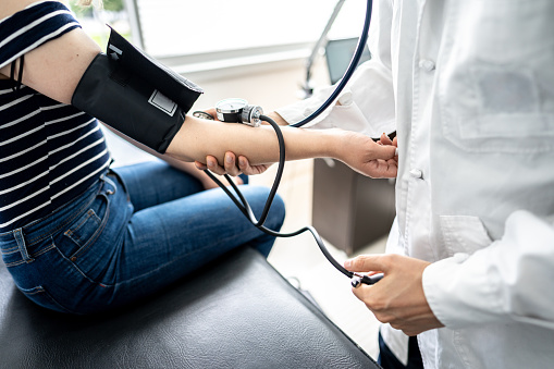 Doctor using a blood pressure gauge on arm of patient at medical clinic