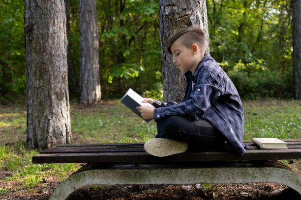istock Schoolboy reading book in the public park 1489234809