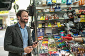 Mature man paying with mobile phone in a newsstand