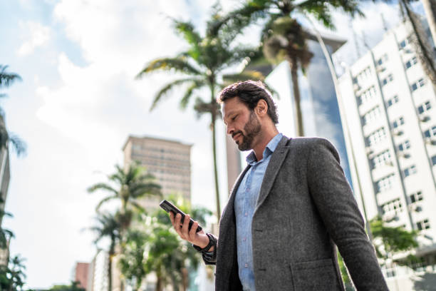 istock Mature man using the mobile phone while walking in the street 1489236053