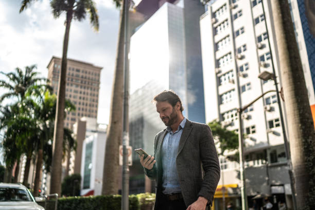 istock Mature man using the mobile phone while walking in the street 1489236572