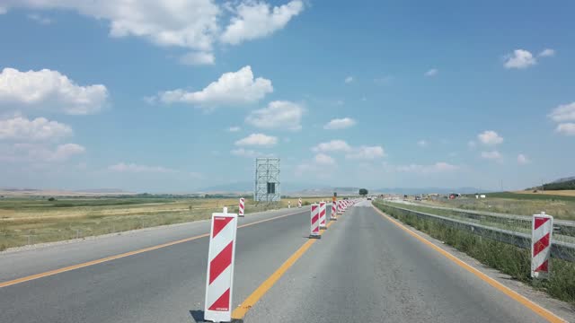 Pov driving on highway road with warning sign posts in a hazard zone during construction road works
