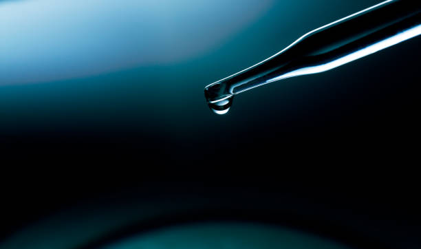 Blue macro science experiment pipette surface,Macro shot of gel with different sized tiny bubbles comes out from chemical dropper into petri dish on blue background. Abstract skincare gel with hyaluronic acid formulation concept