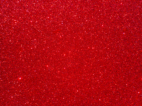 Shiny Red giltter texture christmas abstract background. Starburst effect background in Christmas red. Glitter christmas metallic for design. Brilliant red background for a festive decoration.