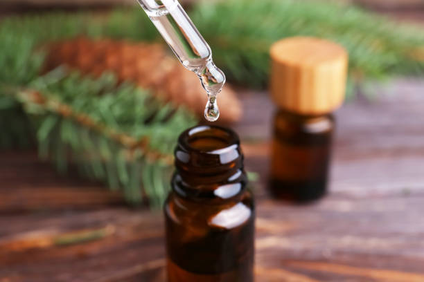 istock Dripping pine essential oil into bottle at wooden table, closeup 1489248659