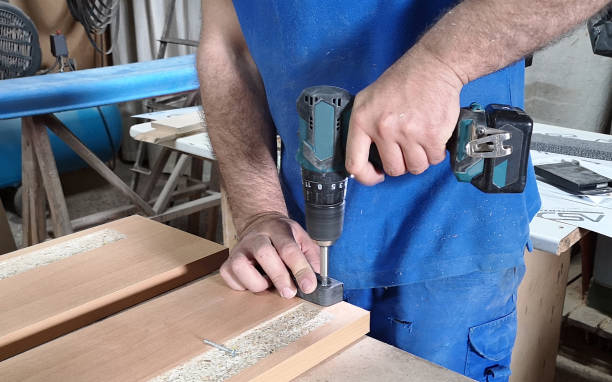 Hands of carpenter uses hand drill to assemble the wood stock photo