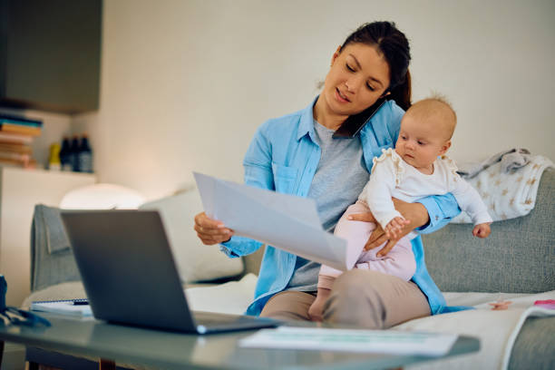 Multi-tasking mother with baby working at home.