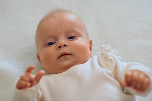istock Cute blue-eyed baby lying down on a bed. 1489253275