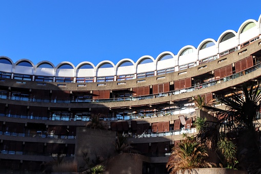 The exterior of curved brutalist apartments with shutters infront of their windows, Barbican, London