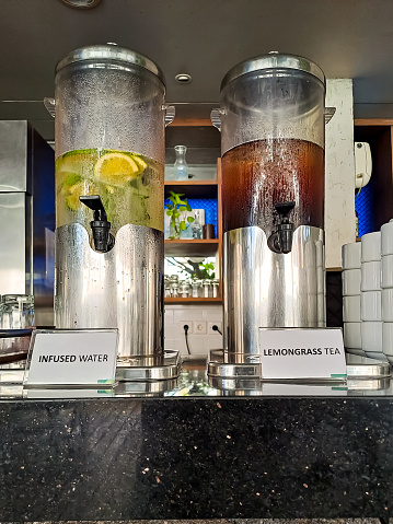 Infused water and lemongrass tea cold drink in dispenser glass on the table of kitchen bar, look fresh