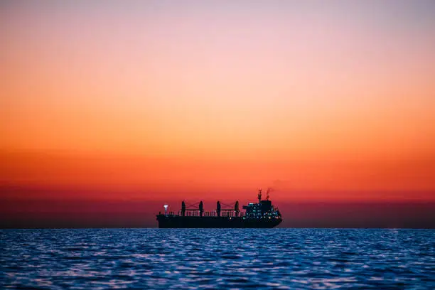 Silhouette of a Large Empty Cargo Ship at Sunset on the Pacific Ocean at Huntington Beach, California near Los Angeles