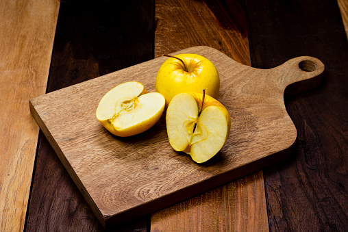 Yellow apple fruit ready to eat on cutting board over wooden table in the kitchen at home