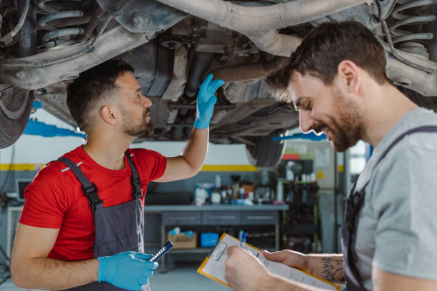 istock Auto mechanics examining underside of car 1489263232