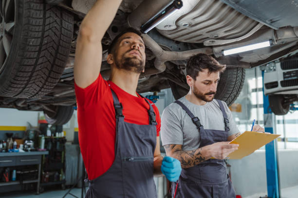 istock Auto mechanics examining underside of car 1489263284