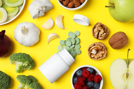 Food and bottle of prebiotic pills on yellow background, flat lay